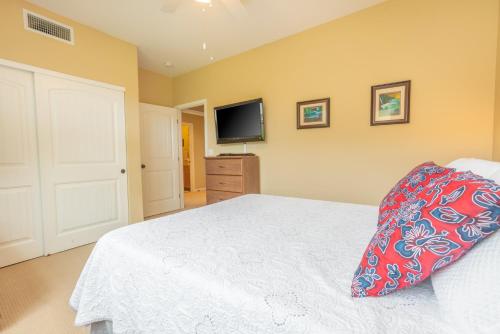 a bedroom with a white bed and a flat screen tv at Princeville Condo with AC, Pool, Garage, Beach Gear 27B in Princeville