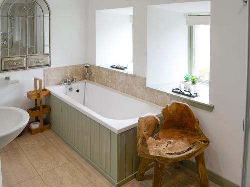 a bathroom with a large tub and a chair at Sunset Cottage in Portmahomack