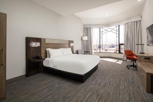 a hotel room with a bed and a large window at Holiday Inn Express Hotel & Suites Ventura Harbor, an IHG Hotel in Ventura