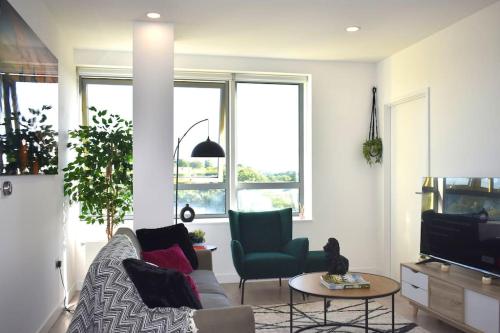 a living room with a couch and a table and windows at Modern 2-Bed Apartment Near Ascot & Legoland, Sleep upto 4 guests, Pet Friendly, Parking Available on Request! in Bracknell