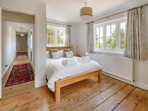 a bedroom with a bed with white sheets and windows at Chittering Farm in Stretham