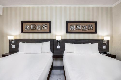 2 bedden in een hotelkamer met witte lakens bij Copantl Hotel & Convention Center in San Pedro Sula