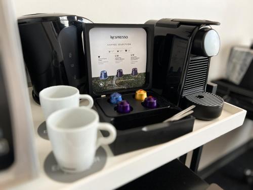 a coffee maker and two cups on a shelf at Edgewater Hotel in Whitehorse