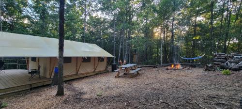 a tent in the woods with a picnic table and a fire at Private place for rest in the forest Tent 1 Forrest Cump in Lenoir