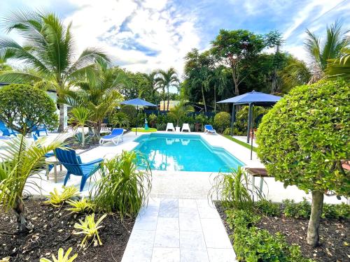 una piscina con sillas y sombrillas azules en The Agustin Guesthouse - Men Only Clothing Optional en Fort Lauderdale