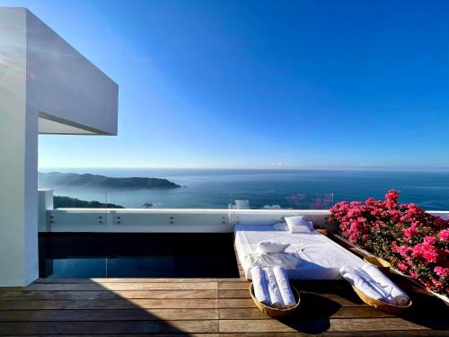 a bed on a balcony with a view of the ocean at Encanto Acapulco in Acapulco