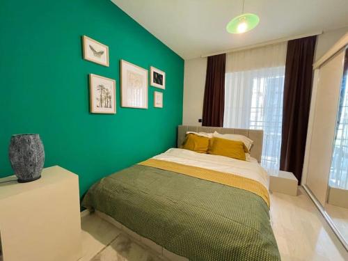 Dormitorio verde con cama y pared verde en Green Downtown Apartment, en Ferizaj