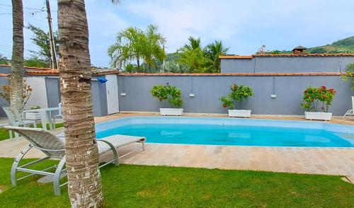 uma piscina com duas cadeiras e uma palmeira em Casa com piscina - Praia do Pernambuco no Guarujá