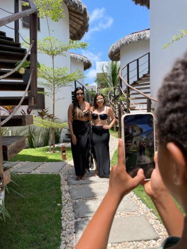 a person taking a picture of two women walking down a sidewalk at Oka Pousada Atins in Atins