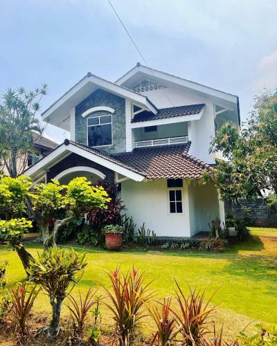 Villa Dedaun Batu في باتو: منزل أبيض مع ساحة خضراء