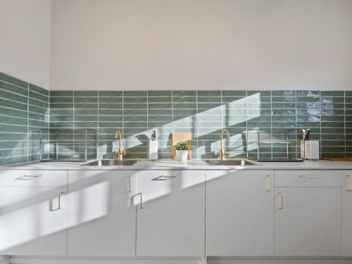 a white kitchen with two sinks and green tiles at Lillou Hostels in Sydney