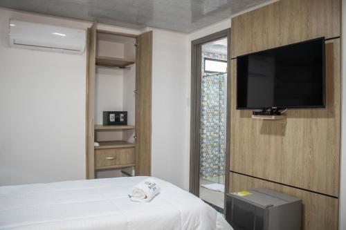 Schlafzimmer mit einem Bett und einem Flachbild-TV in der Unterkunft NORTE REAL HOTEL in Cali