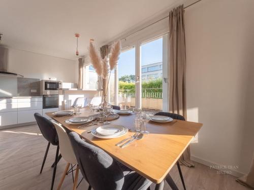 une table de salle à manger avec des chaises et une grande fenêtre dans l'établissement The Nest Torcy, à Torcy