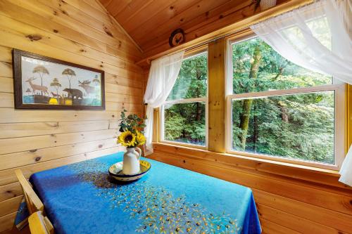a dining room with a blue table and two windows at Beebe Pond Paradise in Castleton