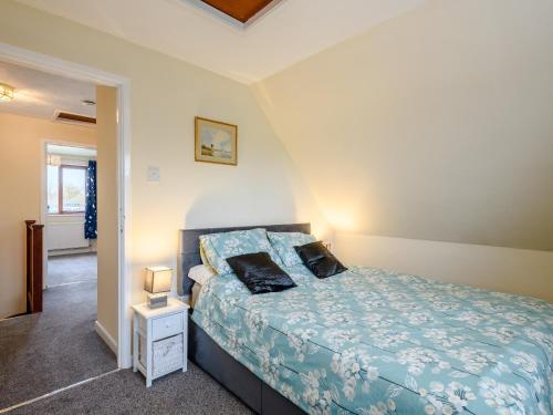 a bedroom with a bed with a blue comforter at Riverside Cottage in Loddon