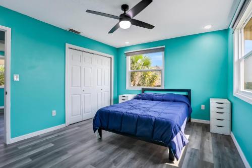 ein blaues Schlafzimmer mit einem Bett und einem Deckenventilator in der Unterkunft Coral Cottage in Weeki Wachee