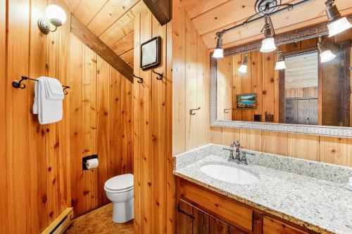 a bathroom with a sink and a toilet and a mirror at Log Cabin Lookout in Bigfork