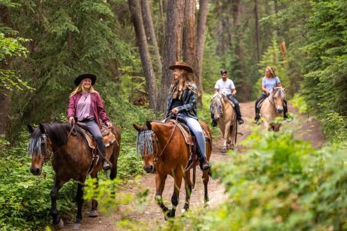 a group of people riding horses on a trail in the woods at Beaver Guest Ranch in Bridge Lake