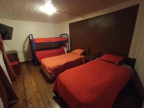 Habitación con 3 camas y sábanas rojas. en Hospedaje Santa Maria y POP, en Osorno