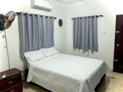 a bedroom with a white bed and blue curtains at Casa Linda 10 mins from Beach-Lagoon in Payita