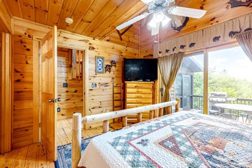 ein Schlafzimmer in einer Hütte mit einem Bett und einem TV in der Unterkunft Cherokee Sunrise Cabin in Mineral Bluff