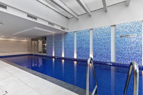 a swimming pool with blue tiles on the walls at Belle Escapes - Oasis on Colley Reserve in Glenelg