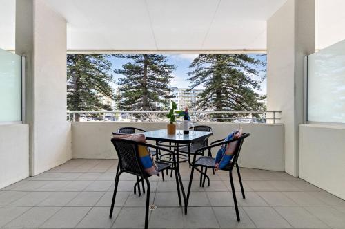 a table and chairs on a balcony with a view of trees at Belle Escapes - Oasis on Colley Reserve in Glenelg