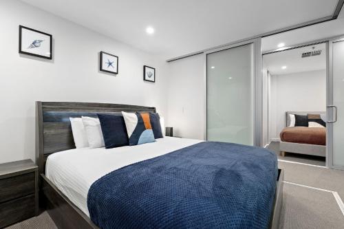 a bedroom with a large bed with a blue blanket at Belle Escapes - Oasis on Colley Reserve in Glenelg