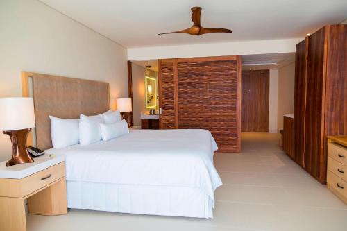 a bedroom with a large white bed with a ceiling fan at The Westin Cozumel in Cozumel