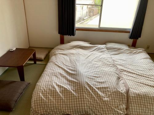 a bed in a room with a table and a window at 民宿 和合 Minshuku WAGO in Tanabe