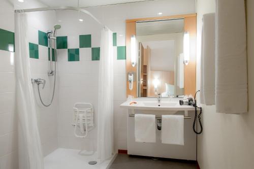 La salle de bains blanche est pourvue d'un lavabo et d'une douche. dans l'établissement ibis Vannes, à Vannes