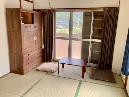 田辺市にある民宿 和合 Minshuku WAGOの椅子と窓のある部屋、キャビネットが備わります。