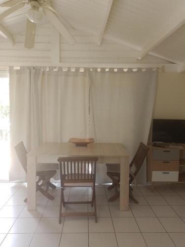 ein Esszimmer mit einem Tisch und Stühlen sowie einem TV in der Unterkunft Résidence Naturelle pour Naturistes in Le Moule