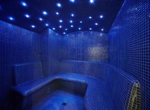 a blue bathroom with a tub with lights on it at Occidental Faro in Faro
