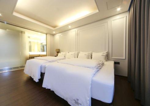 a bedroom with two beds with white sheets at Yangsan Time Square Hotel in Yangsan