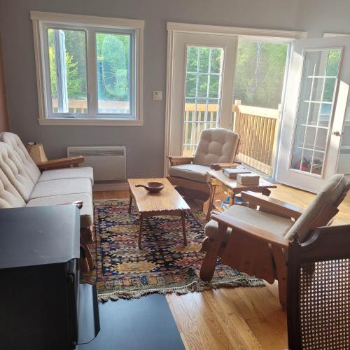 a living room with a couch and chairs and a tv at Le Jasmin chalet complet Rivière Kayak Nature in Saint-Paulin