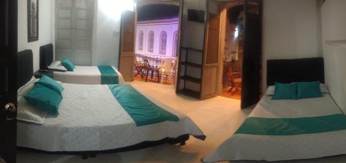 two beds in a room with a room with a door at Hotel San Martin Plaza in Villeta