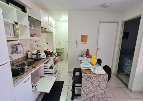 una cocina con armarios blancos y una barra con sillas en Quarto e Sala Monte Paradiso, en Maceió