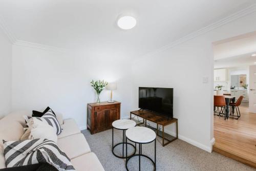 a white living room with a couch and a tv at 'The Fleetwood' Best Local Experience for Couples in Mudgee