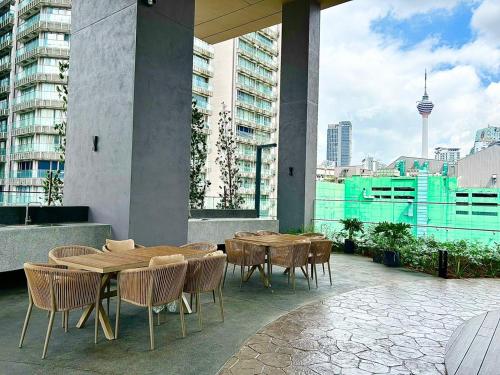 a patio with wooden tables and chairs on a building at Axon Residence at Pavilion KLCC KL Tower view by KIMIRO in Kuala Lumpur