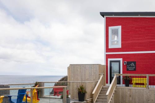een rood gebouw met een terras naast de oceaan bij Cliffs Edge Retreat in Bauline East