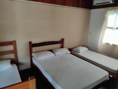 two beds in a small room with a window at Chales Mata Atlantica De Ubatuba in Ubatuba