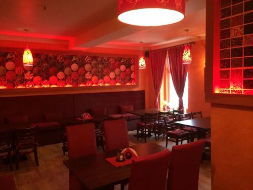 a restaurant with tables and chairs and red lighting at Hotel Cesarski - Kaiserhof in Giżycko