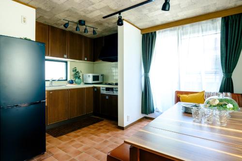 a kitchen with a table and a refrigerator in it at Ikken House in Tokyo
