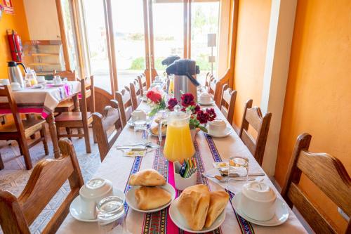 a long table with bread and orange juice on it at Sonqo Killa del Colca in Chivay