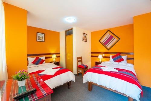 2 camas en una habitación con paredes de color naranja en Sonqo Killa del Colca, en Chivay