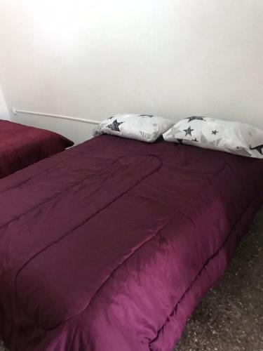 Una cama morada con dos almohadas encima. en Ruta del vino Alojamientos en Maipú