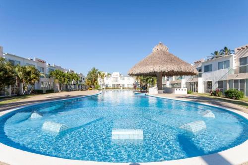 a large blue swimming pool with a straw umbrella at Acapulco Diamante. Casa de descanso in Acapulco