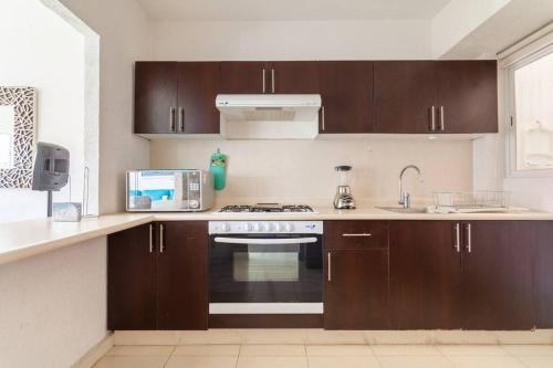 a kitchen with brown cabinets and a stove top oven at Acapulco Diamante. Casa de descanso in Acapulco