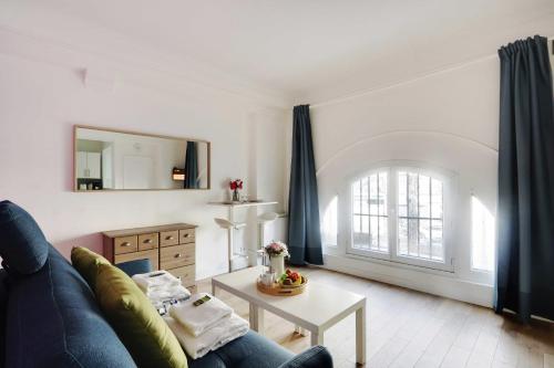 Cozy studio next to Gare de l'Est في باريس: غرفة معيشة مع أريكة زرقاء وطاولة